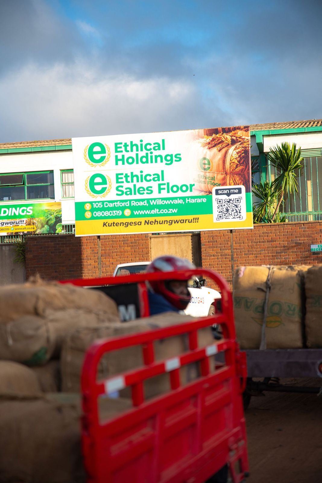 A cargo tricycle stacked with tobacco bales below the Ethical Sales Floor billboard